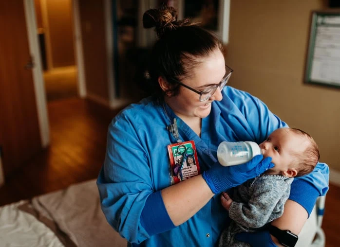 A female nurse feeding a bottle to a baby