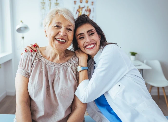 A female medical professional gently comforts a female patient. Both women are smiling