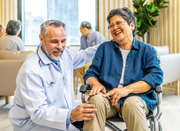 A male doctor laughs with a female patient in a wheelchair